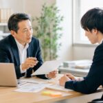 中小企業の社長が若手社員に、やる気を奪わない叱り方で一対一の指導をしている様子