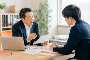 中小企業の社長が若手社員に、やる気を奪わない叱り方で一対一の指導をしている様子