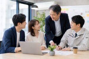 中小企業のベテラン社員と若手社員が笑顔で対話している様子